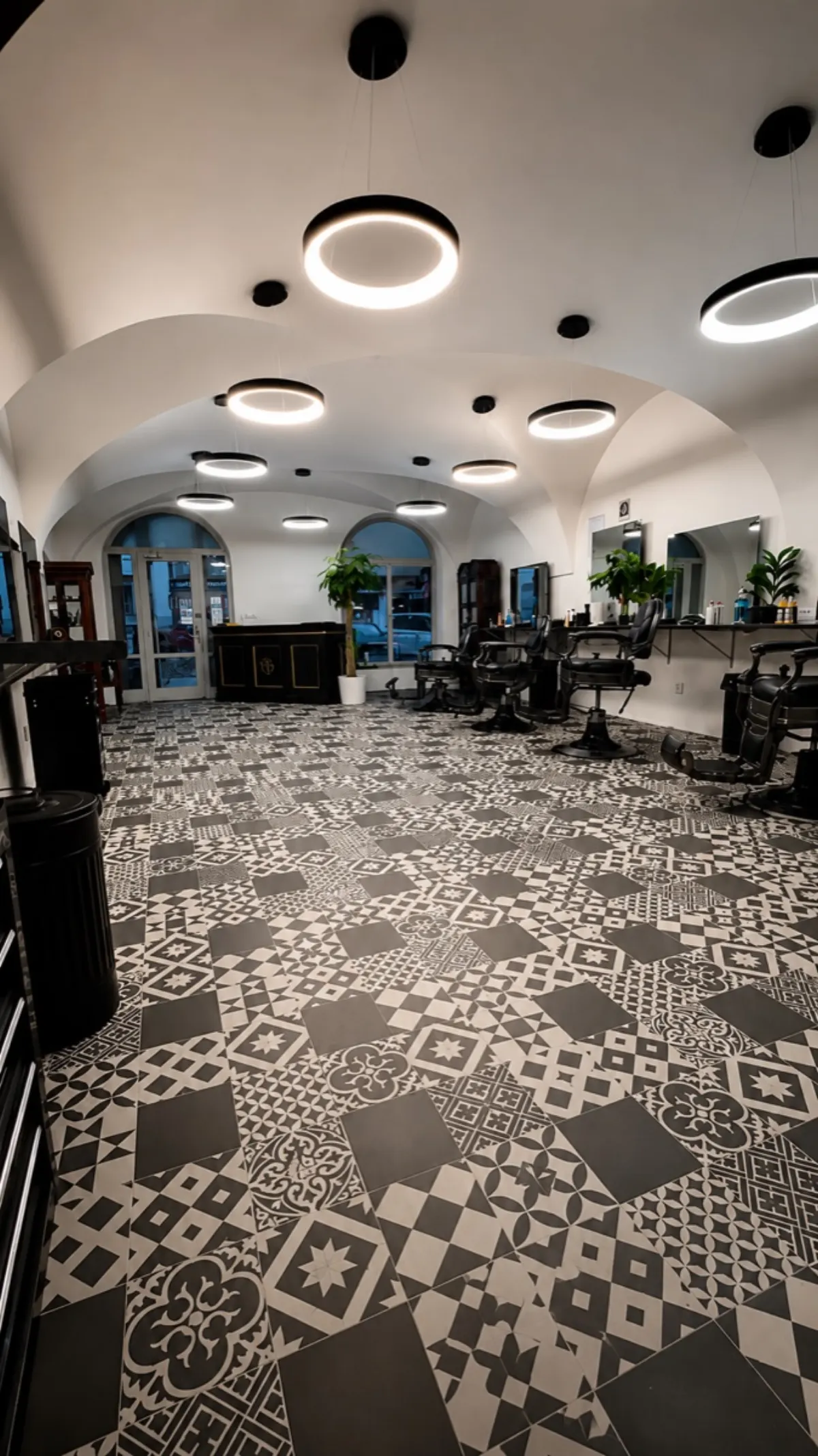 Detail prostor Elite Barbershopu, cementová dlaždicová podlaha s patternem, barber chairs v pozadí