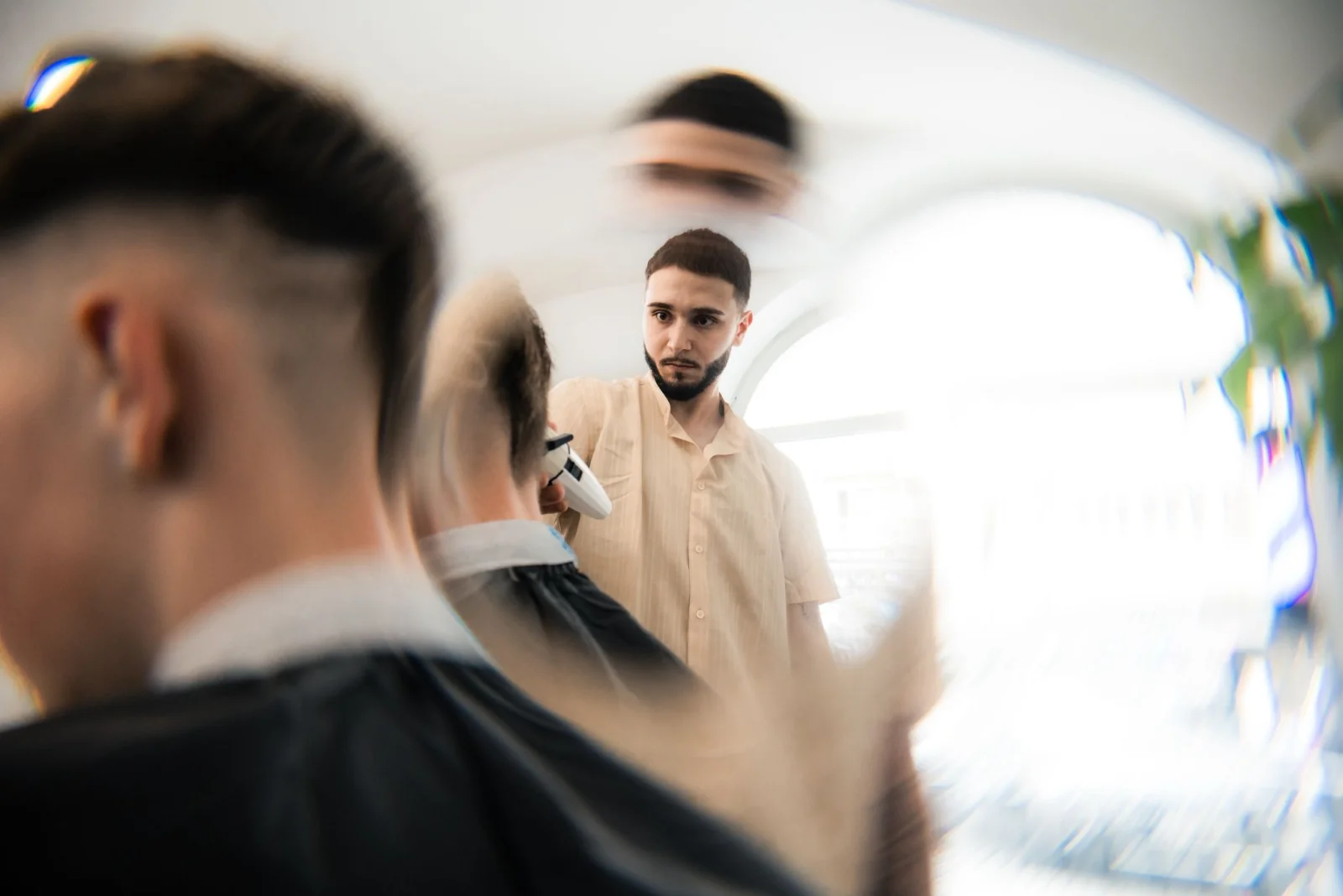 Barber Elite Barbershopu při precizním fade střihu strojkem, klenutý strop a arched window v centru Prahy
